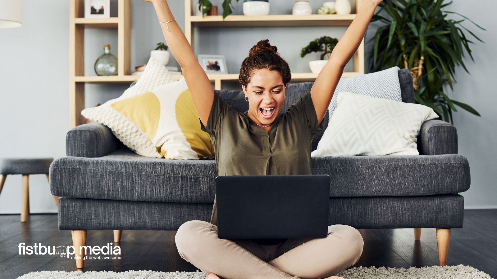 how to use AI to write blog posts Woman sitting on the floor in front of a couch, arms raised in excitement while looking at a laptop screen